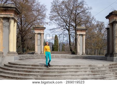 Smiling Enjoying Girl Standing On The Staircase Of The Round Area With Columns, Looking At The Sprin