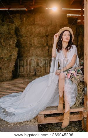 Boho Style Bride Sitting Near Hayloft On Ranch