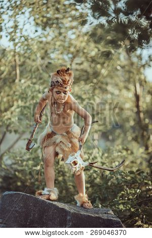 Angry Caveman, Manly Boy With Stone Axe And Animal Skull. Prehistoric Tribal Boy Outdoors On Nature.
