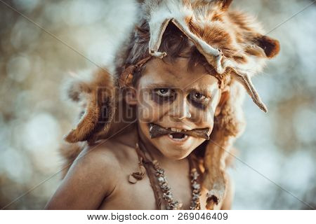 Wild Funny Boy Portrait. Little Caveman With Bone In Mouth. Prehistoric Tribal Boy Outdoors On Natur
