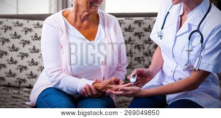 Smiling doctor testing a patients glucose level using a digital glucometer