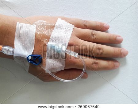 Patient Hand With The Tube Of Normal Saline Infusion On White Cloth Background