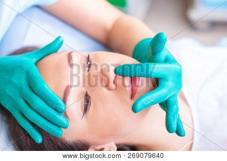 Cosmetic Surgeon Examining Female Client In Clinik  Before Plast