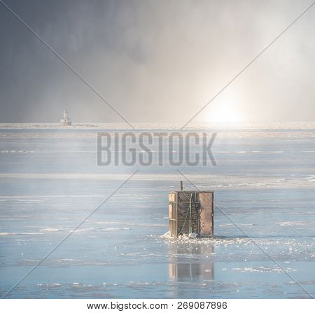 Ice fishing on a misty frozen harbor.