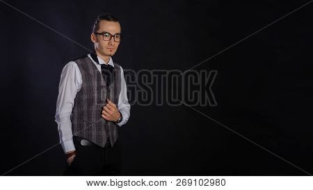 The Handsome Caucasian Young Man In A White Shirt And Suit With Glases Standing, Black Background