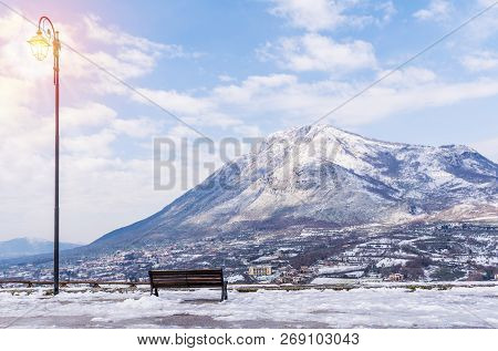 Luminous Street Light And Bench On A Snow-covered Mountain Background. Beautiful Winter Landscape.