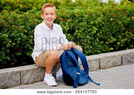 Young Elementary Schoolboy Carrying Backpack. Cheerful Child Standing Outdoor.
