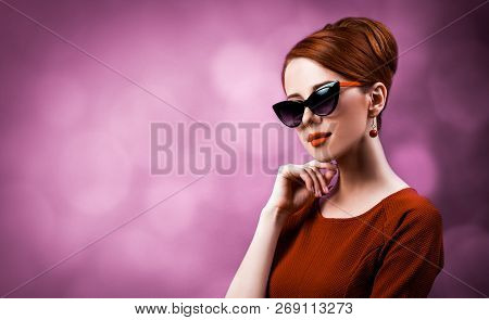 Beautiful Redhead Woman In Sunglasses On Viloet Background.