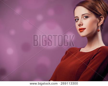 Beautiful Redhead Woman In Red Dress On Viloet Background.