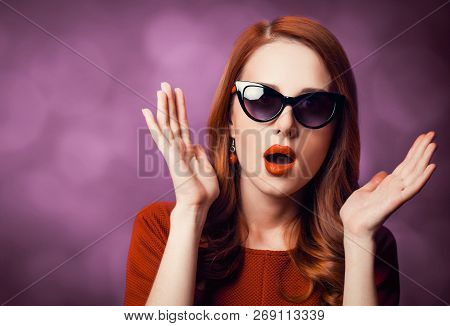 Beautiful Redhead Woman In Sunglasses On Viloet Background.