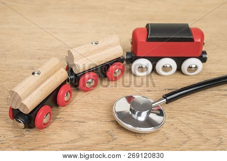 Phonendoscope And Toy Train On The Old Wooden Table