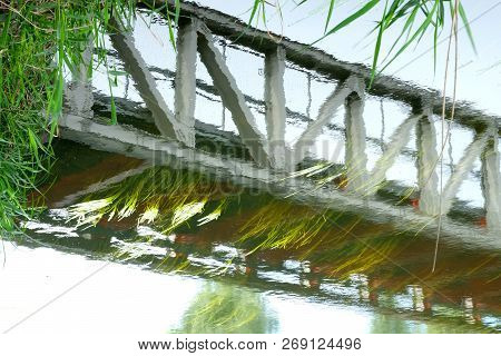 Picturesque Reflection Of A Bridge In Vibrating Water Surface.
