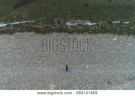 Woman Is Doing Squats The Bodyflex On The Sea Stone Beach. Aerial Beautiful Top View.