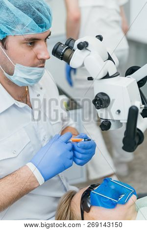 Doctor Used Microscope. Dentist Is Treating Patient In Modern Dental Office. Operation Is Carried Ou