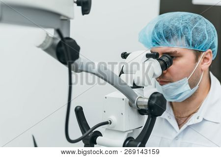 Doctor Used Microscope. Dentist Is Treating Patient In Modern Dental Office. Operation Is Carried Ou