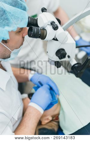 Doctor Used Microscope. Dentist Is Treating Patient In Modern Dental Office. Operation Is Carried Ou