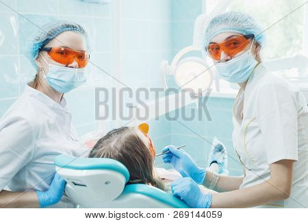 Girl Patient With Dentist And Assistant In A Dental Treatment