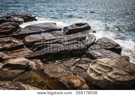 Small Wave Crashing Against The Rocks With Splashes In Selective Focus Daylight