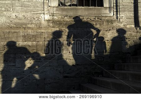 Shadows Of The People On A Real Stone Wall At The New Mosque At Istanbul. Some People Are Sitting An