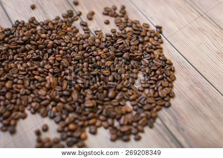 Close Up Coffee Beans Scattered On Wood Background In Selective Focus