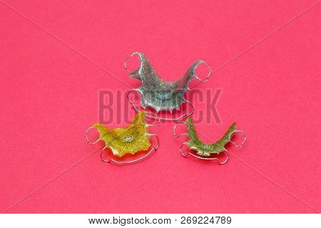 Colorful Dental Braces Or Retainers For Teeth On Pink Background, Closeup