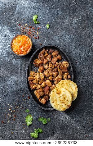 Colombian Food. Fried Pork Chicharron, Arepas And Colombian Tomato Sauce. Top View. Black Background