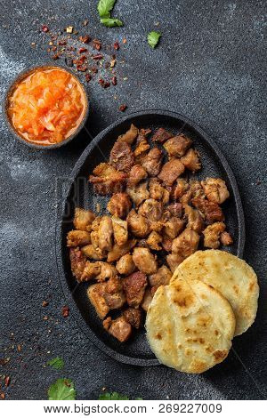 Colombian Food. Fried Pork Chicharron, Arepas And Colombian Tomato Sauce. Top View. Black Background