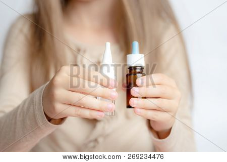 The Little Girl Holds In Hands Two Types Of Nose Drops. Runny Nose In Children.