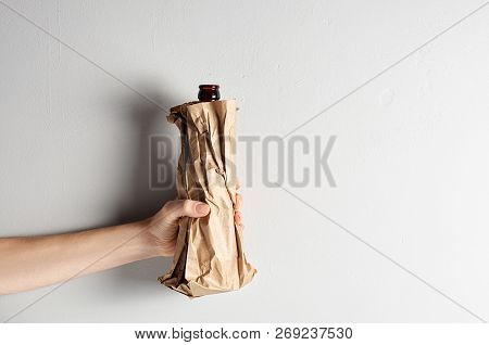Hand Holding Beer Bottle In The Paper Bag On Gray Concrete Background