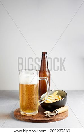 Lager Beer In Glass And Bottle With Potato Chips On Gray Concrete Background