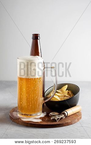 Lager Beer In Glass And Bottle With Potato Chips On Gray Concrete Background