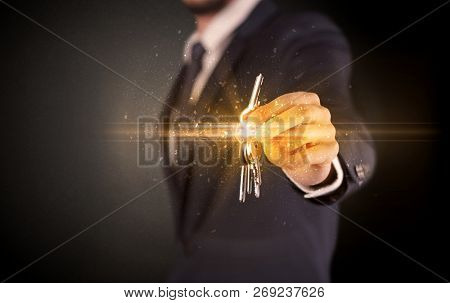 Businessman hand  over shiny keys in dark suit with dark background