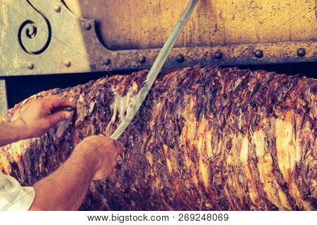 Chef Dressed In Red Cutting Turkish Cag Kebab In Display