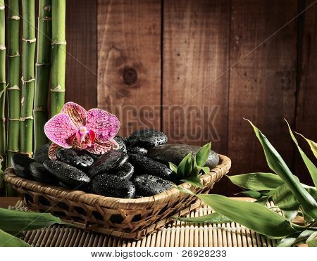 koostumus bamboo grove, vaaleanpunainen orkidea ja musta zen kivet kulhoon puinen tausta