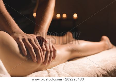 A Masseur In A Dark Room Does A Hip Massage With Oil For A Woman. Spa Procedures Massage Women