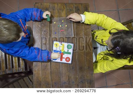 Little Brothers Playing Parchis Over Wooden Vintage Table. Overhead View. Traditional Board Game