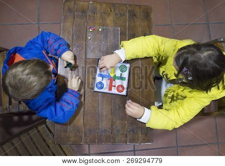Little Brothers Playing Parchis Over Wooden Vintage Table. Overhead View. Traditional Board Game