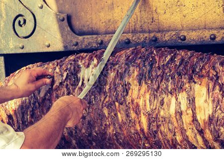 Chef Dressed In Red Cutting Turkish Cag Kebab In Display