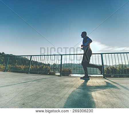 Attractive Wiry Man Jogging Against To Sun. Regular Morning Training At Sea. Young Sportsman Jogging