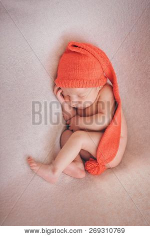 A Naked Newborn Baby Sleeps In A Christmas Hat.