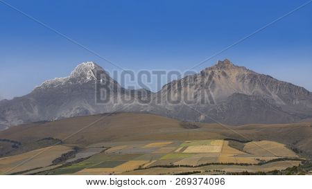 Landscape View Of Cultivated Fields With Ilinizas Mountains In The Background On A Summer Day