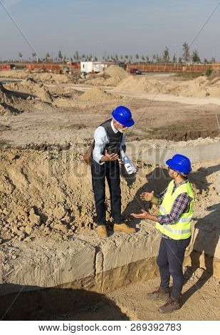 Senior Architect Explaining Project To A Younger Construction Worker At Building Site