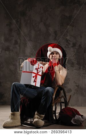 Christmas Gift Concept. Man In Santa Hat Bring Gift For You. Attractive Man Hold Box.  Christmas And
