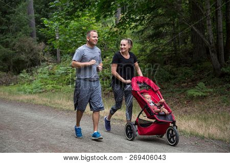 Couple exercising and jogging together pushing their baby in a stroller