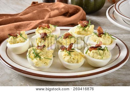 A Plate Of Deviled Eggs With Chives And Bacon Bits