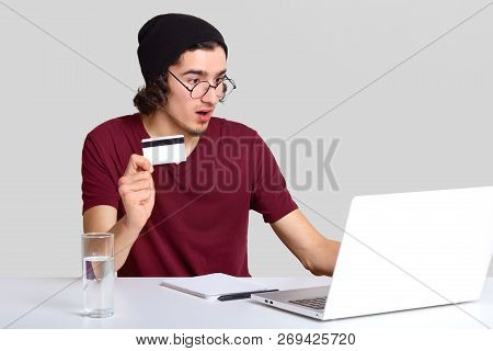 Shocked Male With Appealing Appearance, Holds Plastic Card In Hand, Being Terrified As Checks Bank A