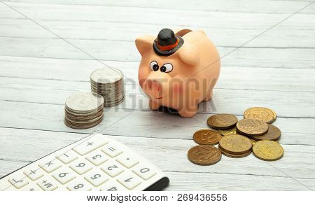 Ceramic Piggy Bank With Coins On A Wooden Background, Close-up