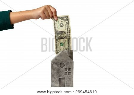 Hand Of Anonymou Kid Holding Dollar Banknote Over Stone Toy Houses On White Background