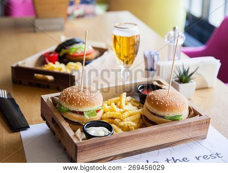 One Black Colored And Two Normal Small Mouth-watering, Delicious Burgers On The Wooden Tray Served W