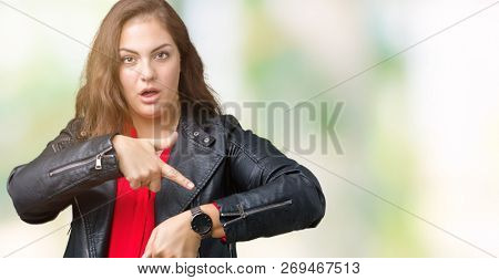 Beautiful plus size young woman wearing a fashion leather jacket over isolated background In hurry pointing to watch time, impatience, upset and angry for deadline delay